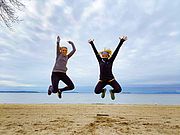 Two women jumping with joy in front of Lake Champlain.