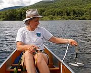 Photo of a woman in a canoe holding a secchi disk into the water