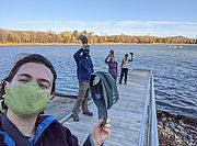 Photo of LCC's Staff and Support Team on a dock taking their hats off to show appreciation for their volunteers.