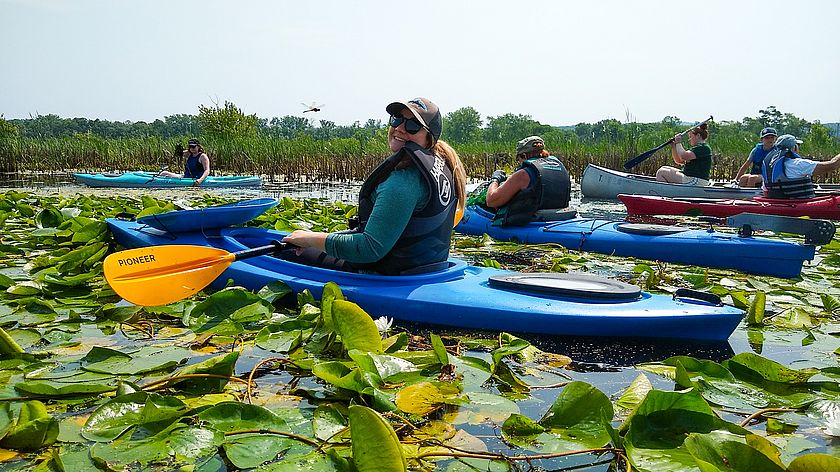 A smiling woman paddling a kayak.