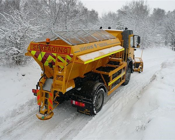 A utility truck spreading salt on a snowy road during winter.