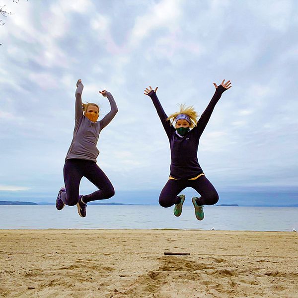 Two women jumping with joy in front of Lake Champlain.